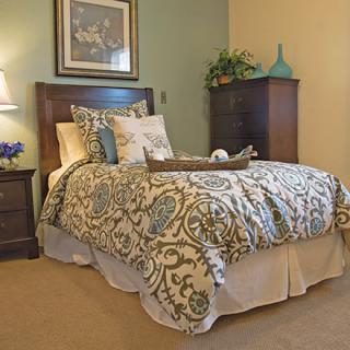 A cozy bedroom with a well-decorated bed, bedside table with a lamp, and framed artwork on the wall.