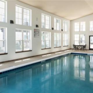 A spacious indoor swimming pool with large windows allowing natural light to fill the room.