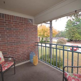 A cozy balcony with chairs overlooking a view of autumn trees.