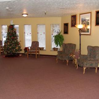 A cozy lobby with a Christmas tree, chairs, and warm decor.