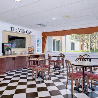 A cozy cafe area with checkered flooring, seating arrangements, and a coffee station.