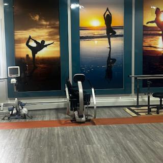 A modern gym space featuring fitness equipment and inspiring wall art of yoga and exercise at sunset.