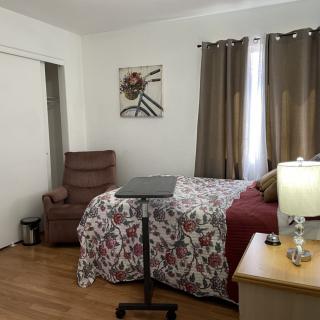 A cozy bedroom with a floral bedspread, armchair, and warm lighting.