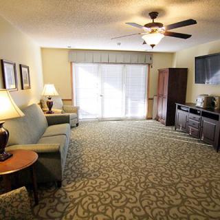 A spacious living room with a sofa, television, and ceiling fan.