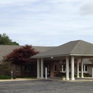 A welcoming entrance to a residential or commercial building surrounded by green trees and a cloudy sky.