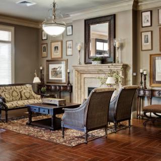 A cozy and elegantly designed living room featuring a fireplace, upholstered furniture, and decorative wall art.