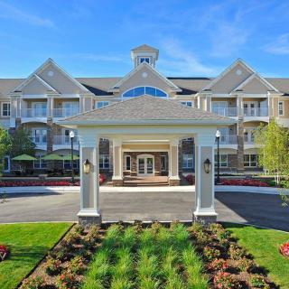 A grand residential building with a landscaped entrance and clear blue sky.