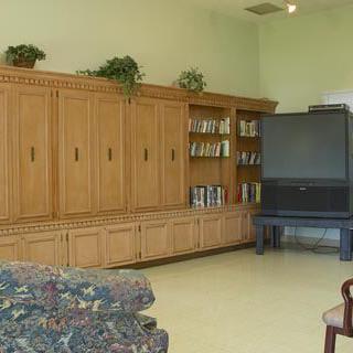A spacious living room with a large entertainment center and television, featuring wooden cabinetry and a comfortable couch.