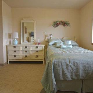 A cozy bedroom featuring a neatly made bed and a dresser with a mirror.