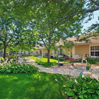 A serene garden with lush greenery and a sunlit pathway leading to a cozy house.