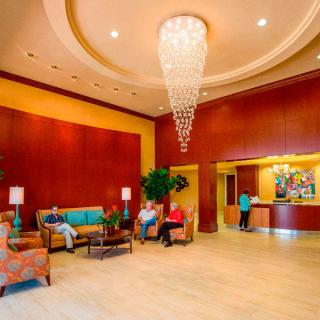 A spacious hotel lobby with a striking chandelier, comfortable seating area, and reception desk.