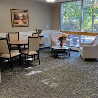 A cozy living area featuring a dining table, chairs, and comfortable seating by a large window.