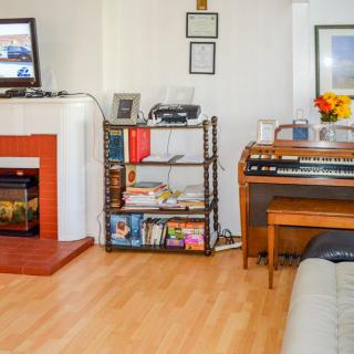 A cozy living room with a fireplace, television, bookshelves, and an organ.