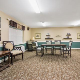 A neatly arranged meeting room with chairs and a table, featuring carpet flooring and decorative elements on the walls.