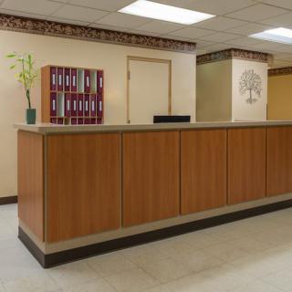 A reception desk in an office setting with wood paneling and neutral decor.