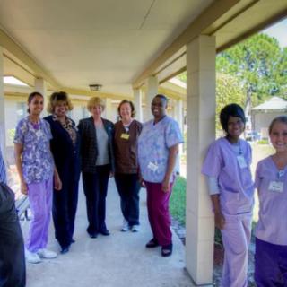 A group of healthcare workers in uniforms posing for a photo outdoors.