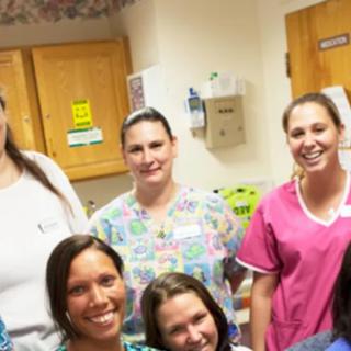 A group of nurses smiling in a healthcare setting.