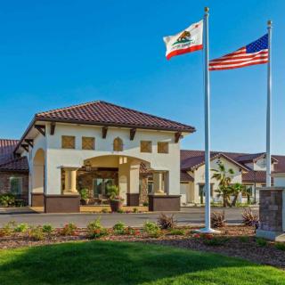 A building with California and U.S. flags waving in front under a clear blue sky.