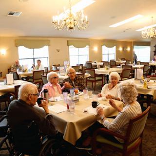 A group of seniors socializing in a communal dining area.