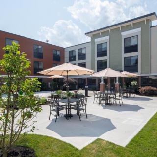 A modern outdoor patio area with tables and umbrellas at the back of a building.