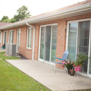 A brick house with a patio, featuring sliding glass doors and outdoor seating with flowers.