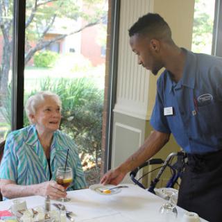 A server attending to an elderly customer in a dining setting.