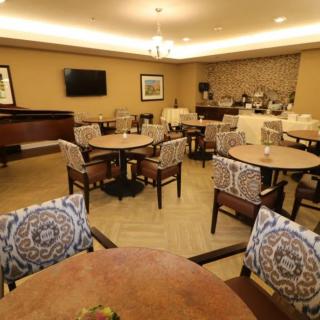 A cozy dining area with tables, chairs, a piano, and a buffet setup.