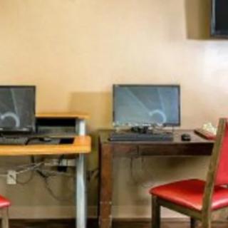 A small office setup with two computers on separate desks, each accompanied by a red chair.