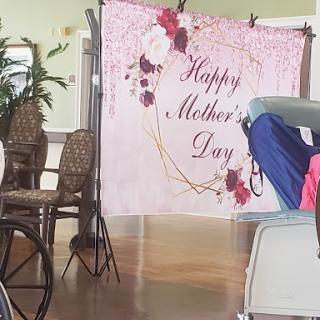 A decorative backdrop celebrating Mother's Day, adorned with flowers and a warm greeting.