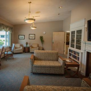 A cozy living room with comfortable seating, a fireplace, and ample lighting.