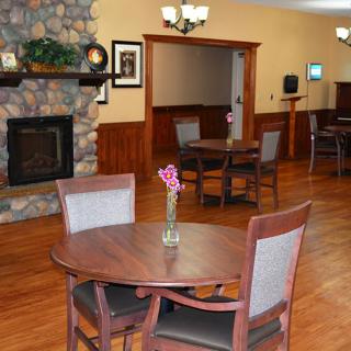 A cozy indoor dining area with wooden tables and chairs, featuring a stone fireplace and warm decor.