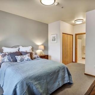 A cozy and modern bedroom featuring a comfortable bed with decorative pillows, ambient lighting, and stylish wooden accents.