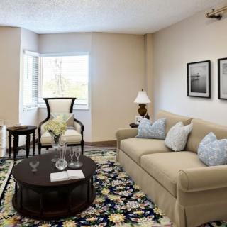 A cozy living room with a beige sofa, armchair, and floral rug.