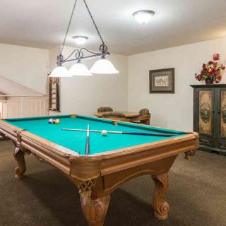 A cozy recreation room featuring a classic pool table under warm lighting.