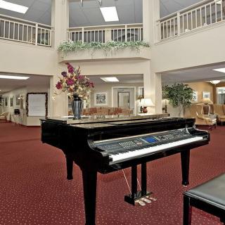 A hotel lobby featuring a grand piano on a red carpet with elegant decor.