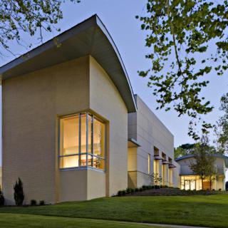A modern building with large windows, showcased in the evening light.