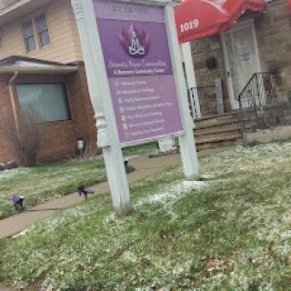 A business sign in front of a building, surrounded by grass and light snow.