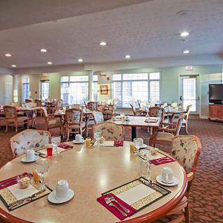 A spacious dining area with neatly arranged tables and chairs, well-lit and ready for guests.