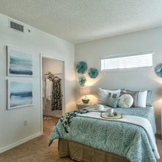 A modern bedroom with elegant decor, featuring a neatly made bed and artistic wall accents.
