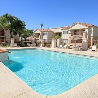 A sunny day at a residential apartment complex featuring an inviting outdoor swimming pool.