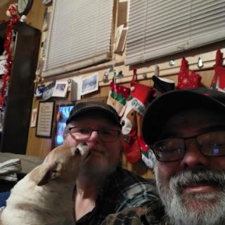 A cheerful selfie with friends and a playful dog, surrounded by festive decorations.