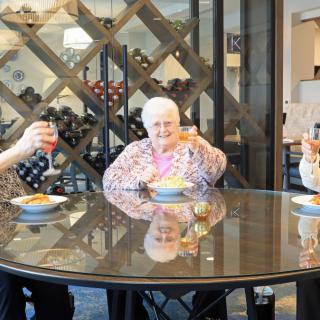 A group of elderly people enjoying a meal together at a round table in an indoor setting.