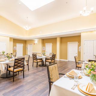 An elegantly decorated dining room with neatly arranged tables and chairs under bright lighting.
