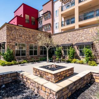 A modern apartment complex featuring a stone facade and a central courtyard with a fire pit.