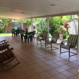 A spacious covered patio with chairs and a table, overlooking a lush garden.