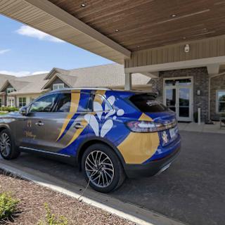 A branded vehicle parked outside a building, featuring a blue and yellow design.