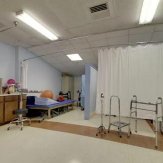 A hospital room with medical equipment, including a bed, walker, and privacy curtain.