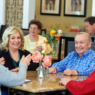 A group of seniors enjoying a meal and conversation at a dining table.