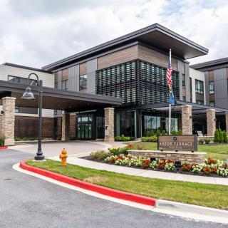 A modern hospital building with a landscaped entrance and an American flag.