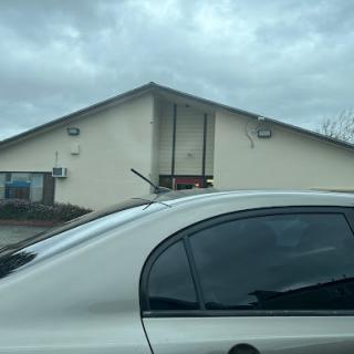 A white car parked beside a building under a cloudy sky.